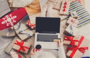 Woman makes christmas shopping online with laptop, above view